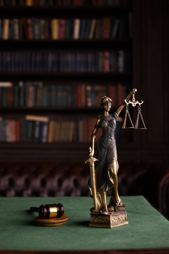 who-we-are Lady Justice and gavel on a table in a classic law library setting.